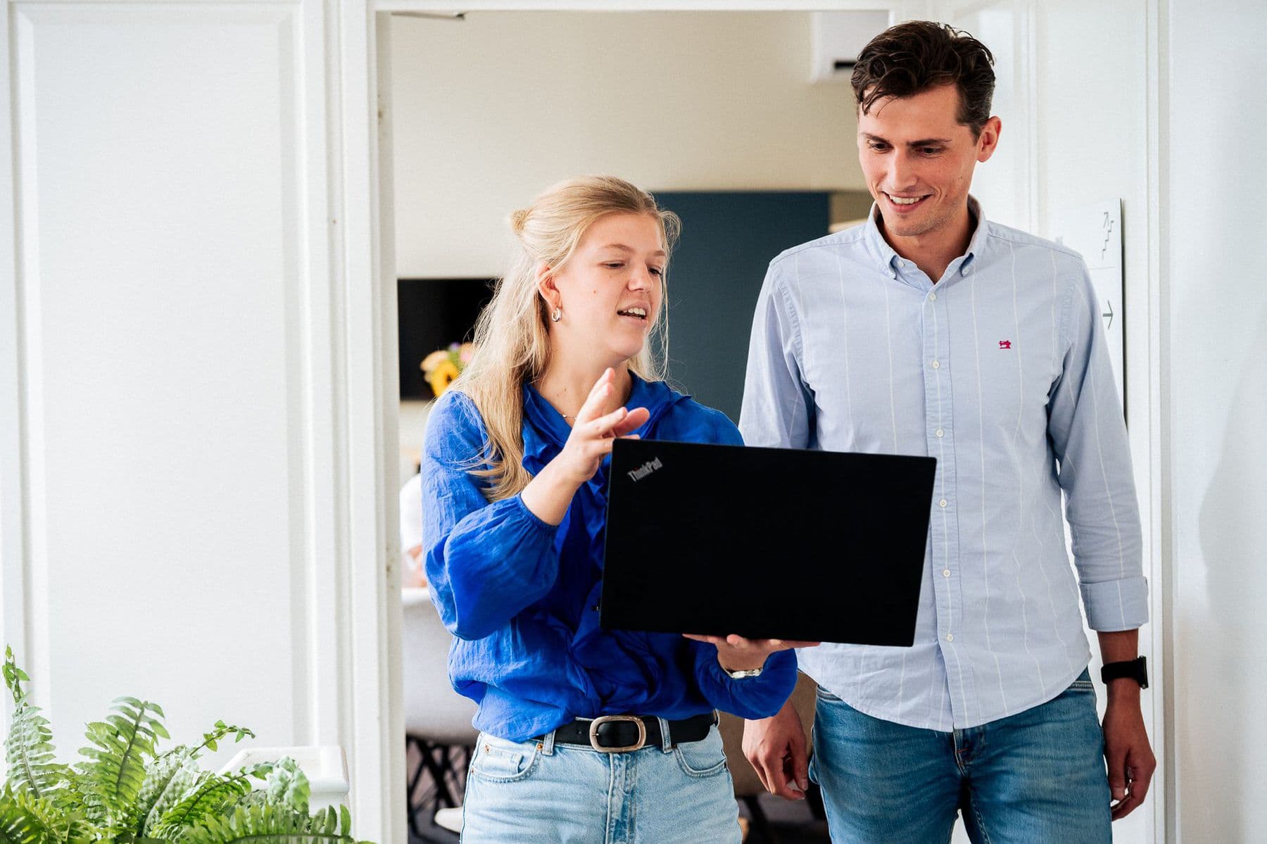 Een collega laat een tweede collega iets zien op een laptop, in de gang van Villa Mooi Zeist