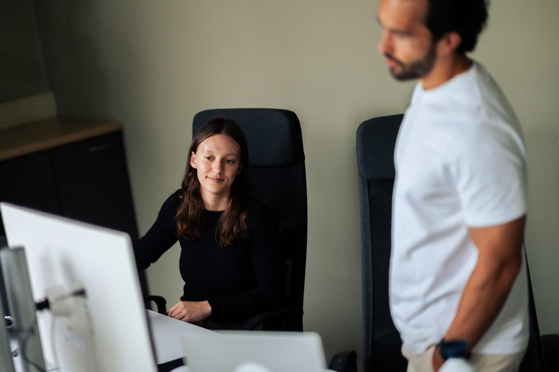 Een collega kijkt vanachter haar scherm mee terwijl een tweede collega langsloopt